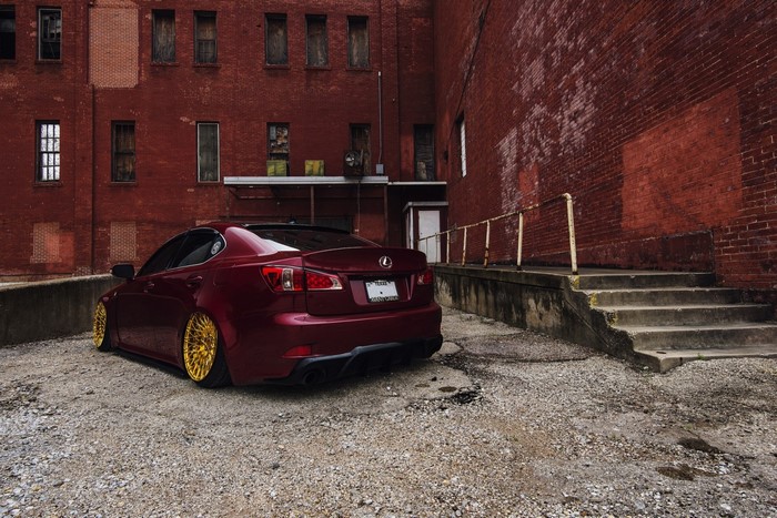 Maroon Lexus IS F with gold wheels parked by brick building