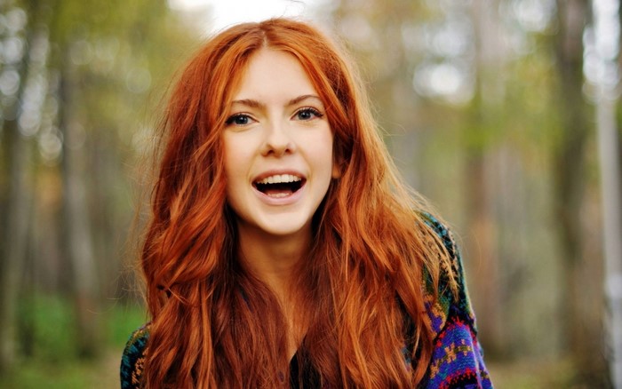 Young woman with long red hair smiling outdoors