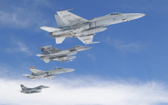 Four fighter jets flying in formation against a blue sky