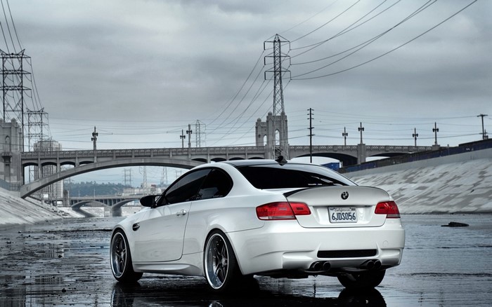 White BMW M3 Coupe parked in a dry riverbed with bridges