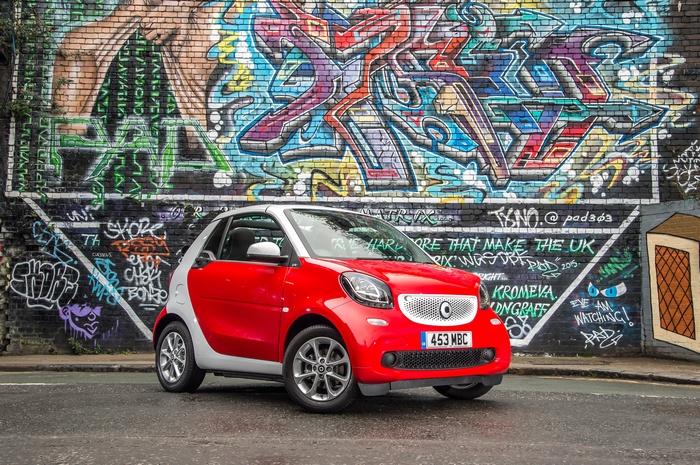 Red Smart Fortwo Passion Cabriolet parked in front of graffiti wall