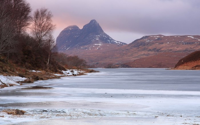 Frozen lake with mountains and bare trees