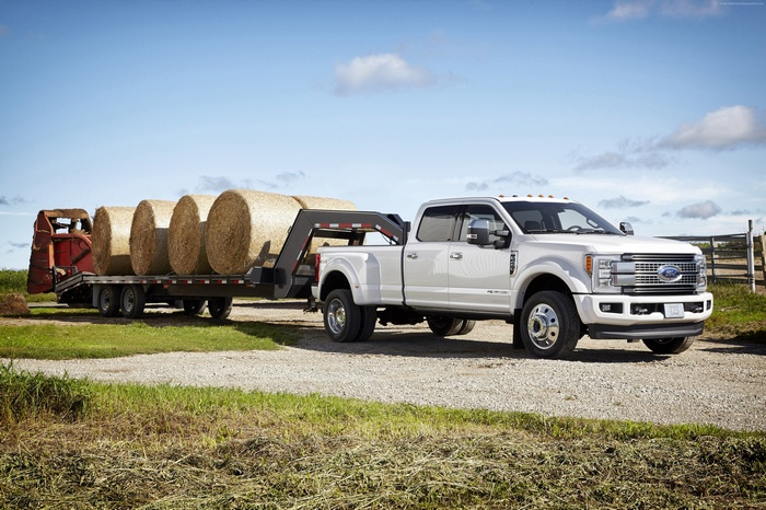 White Ford F450 Super Duty Platinum Crew Cab Truck Towing Hay Bales