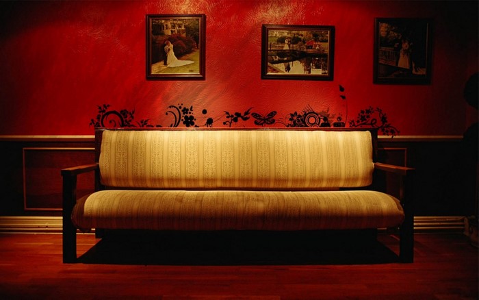 Couch in a red room with framed pictures