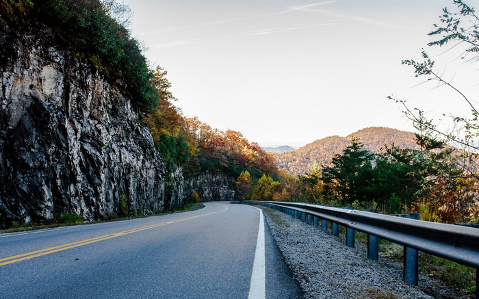 Mountain road with guardrail and autumn foliage