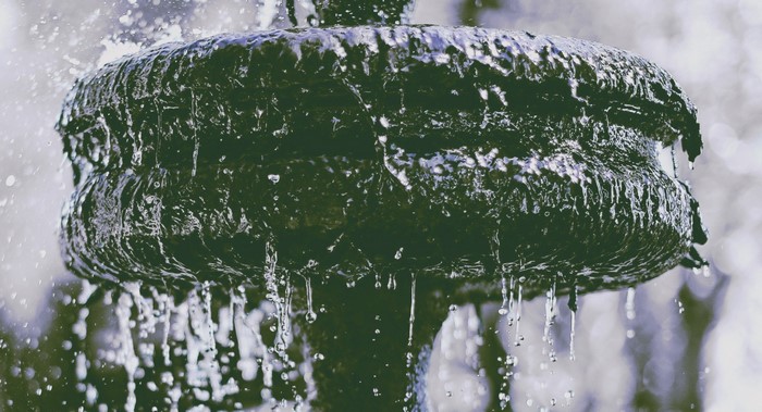 Water flowing over a dark, textured fountain