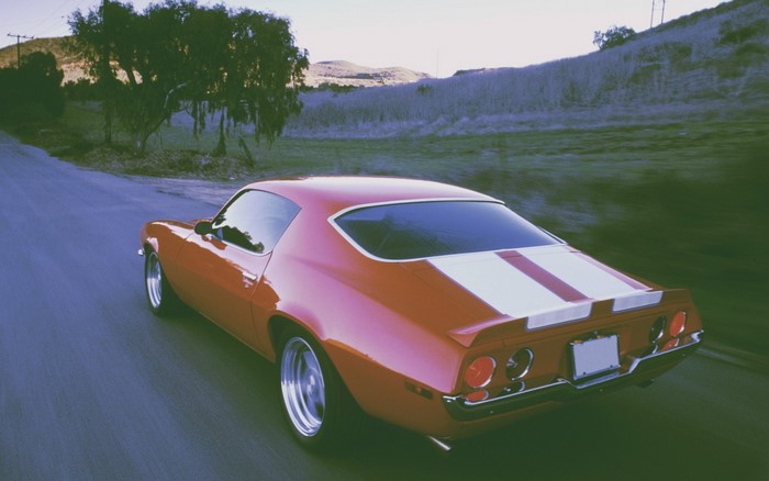 Red Chevrolet Camaro Z28 driving on a road