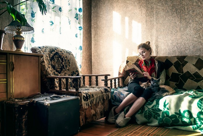 Woman reading a book with cats on her lap