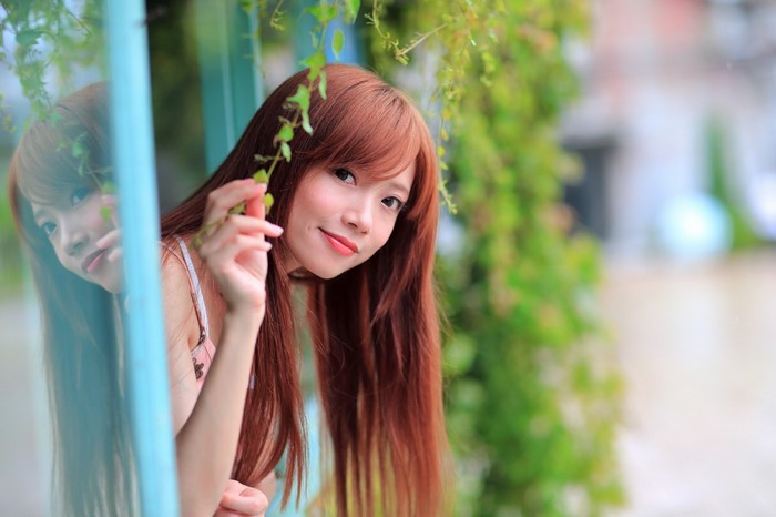 Portrait of Woman with Long Red Hair Among Greenery