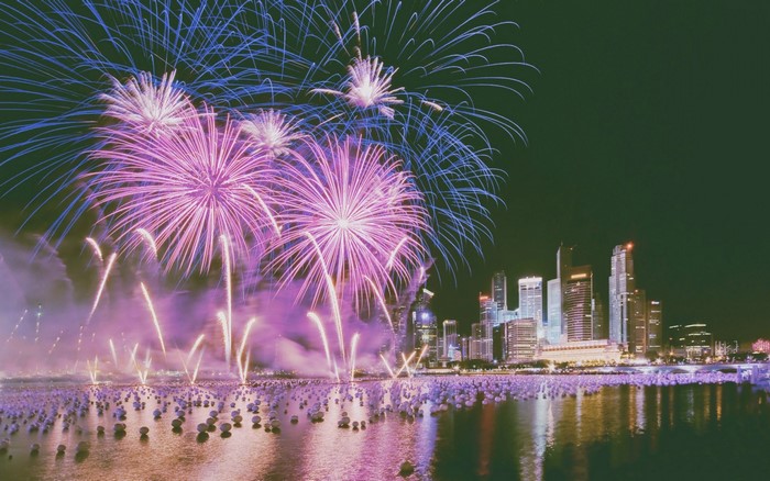 Fireworks display over a city skyline and water