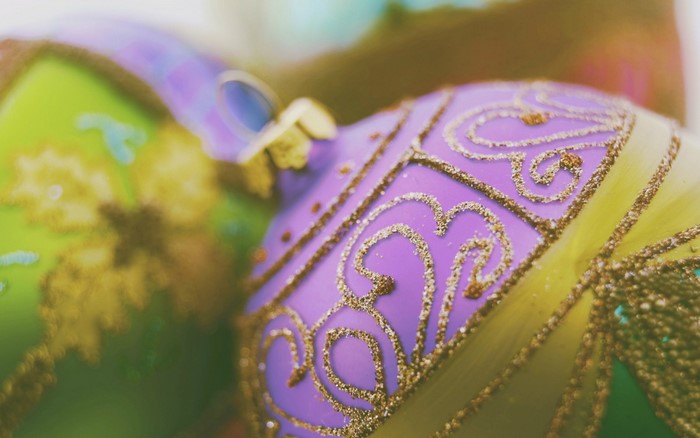 Close up of purple and green Christmas ornaments with gold patterns