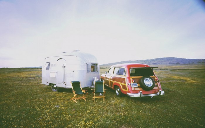 Vintage Airstream trailer and woody station wagon in a field