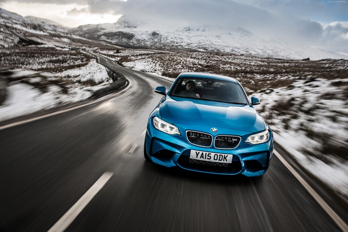 Blue BMW M2 Coupe driving on a snowy mountain road