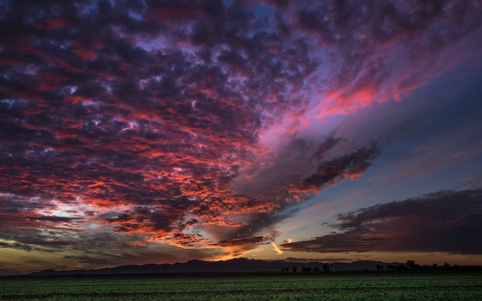 Dramatic sunset clouds over a field and mountains