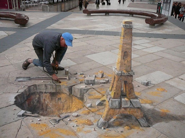 Man painting 3D Eiffel Tower street art on pavement