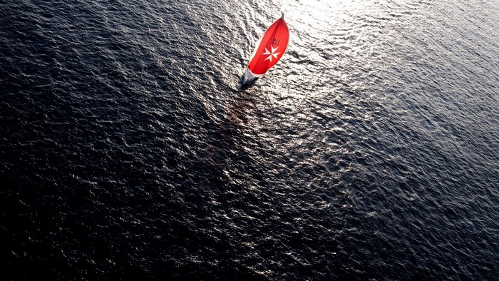 Sailboat with red sail on dark water