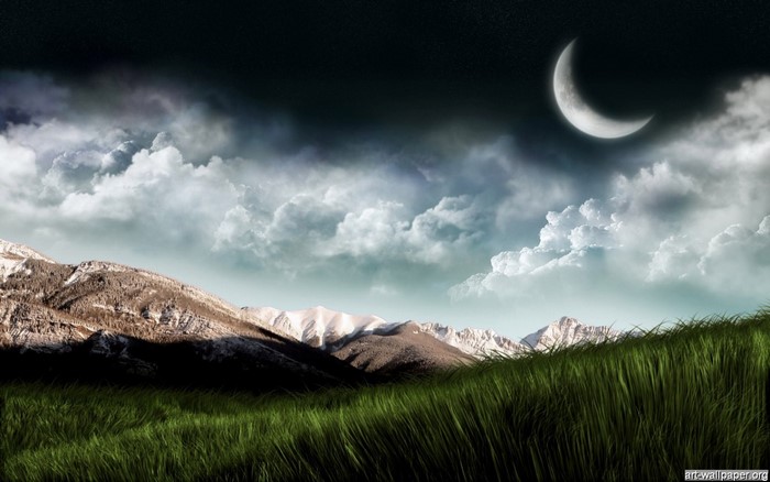 Crescent moon over mountains and grassy field