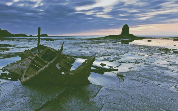 Shipwreck on a rocky shore at sunset