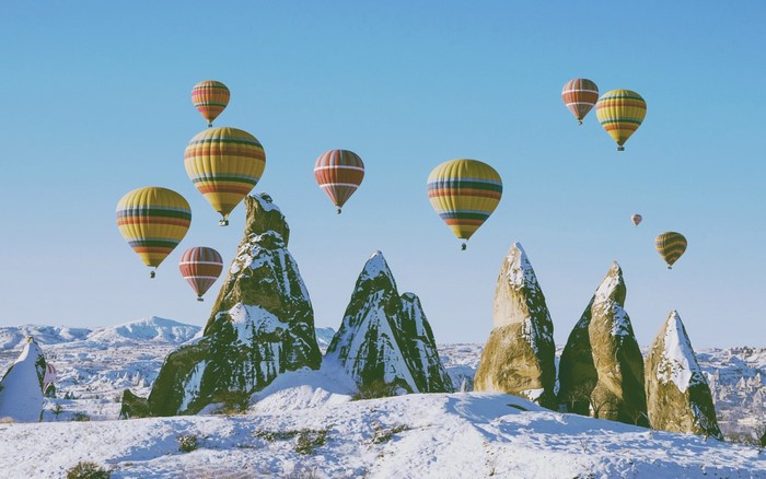 Hot air balloons over snowy rock formations