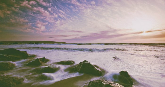 Ocean waves crashing on rocks at sunset