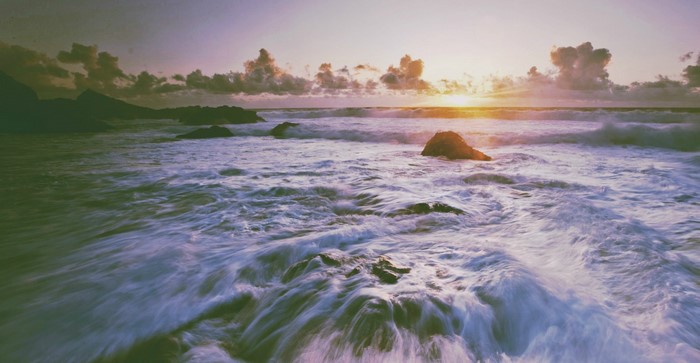 Ocean waves crashing on rocks at sunrise