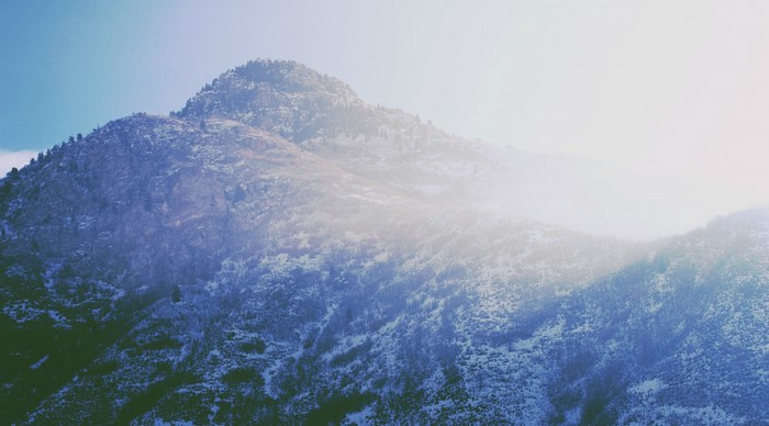 Snow-covered mountain peak with sunlight and mist