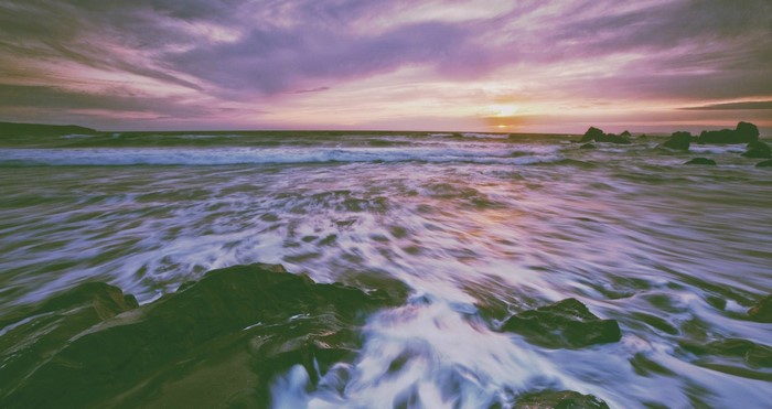 Sunset over the ocean with waves and rocks