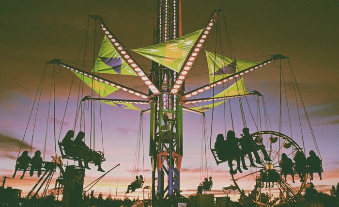 Amusement park swing ride and ferris wheel at dusk
