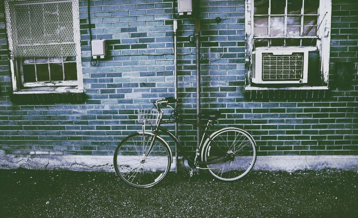 Bicycle parked against a brick wall with windows