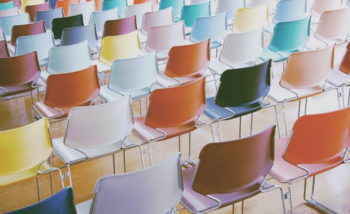 Rows of colorful plastic chairs in an empty room