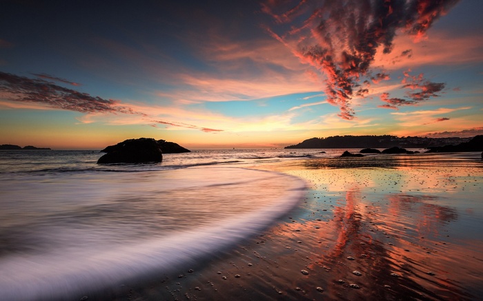 Sunset over a rocky beach with colorful clouds