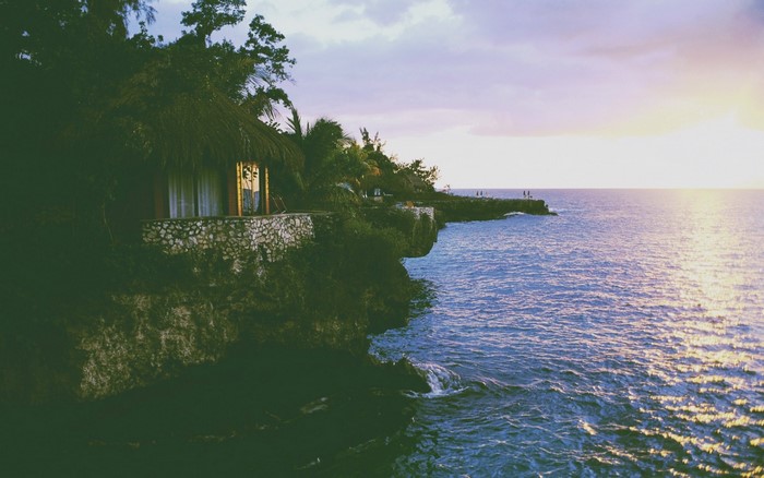 Thatched hut on a cliff overlooking the sea at sunset