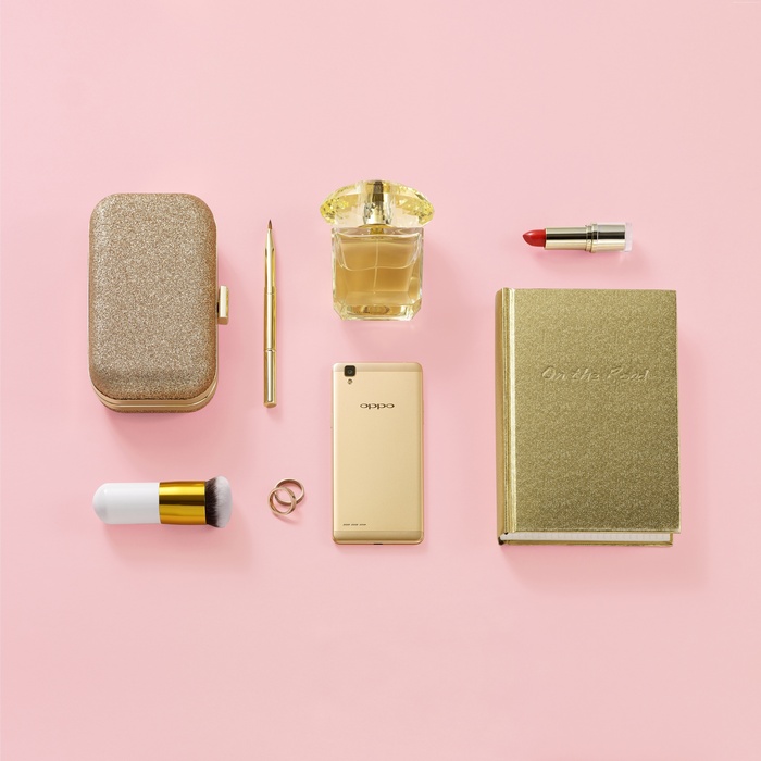 Gold clutch, perfume, lipstick, Oppo phone, and notebook