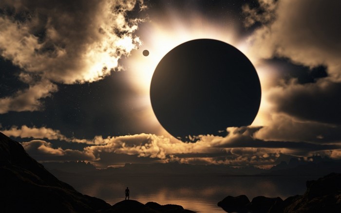 Solar eclipse over a rocky shore with a lone figure