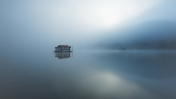 Floating house in mist on a lake at dawn