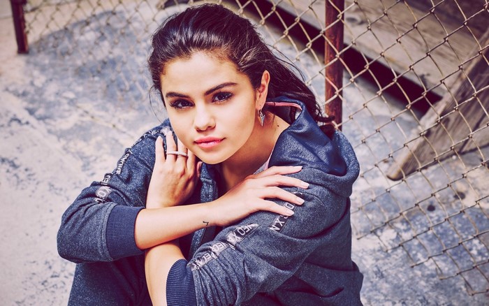 Selena Gomez posing in a hoodie