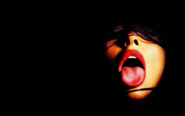 Close up of a woman's face with open mouth and red lipstick