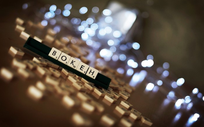 Scrabble tiles spelling BOKEH with bokeh lights