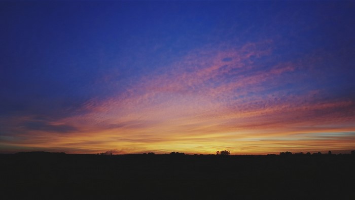 Silhouette of a field at sunset with colorful clouds