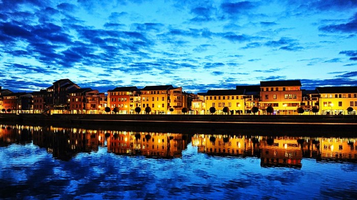 Cityscape with buildings reflecting in a river at dusk