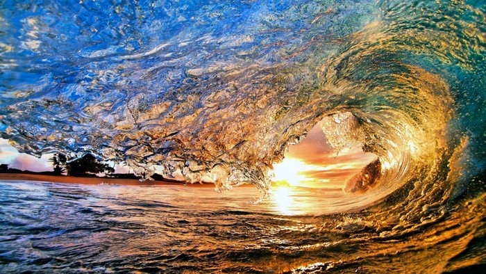 Wave crashing at sunset with sunlight reflecting on water