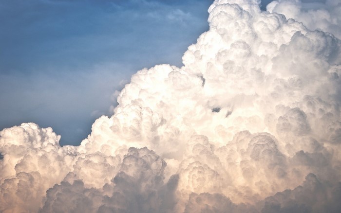Sunlight illuminating dramatic cumulus clouds in a blue sky