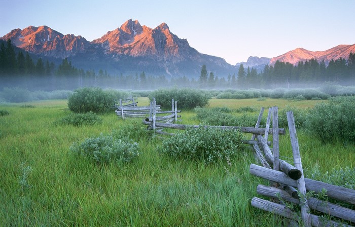 Foggy mountain valley with wooden fence at sunrise