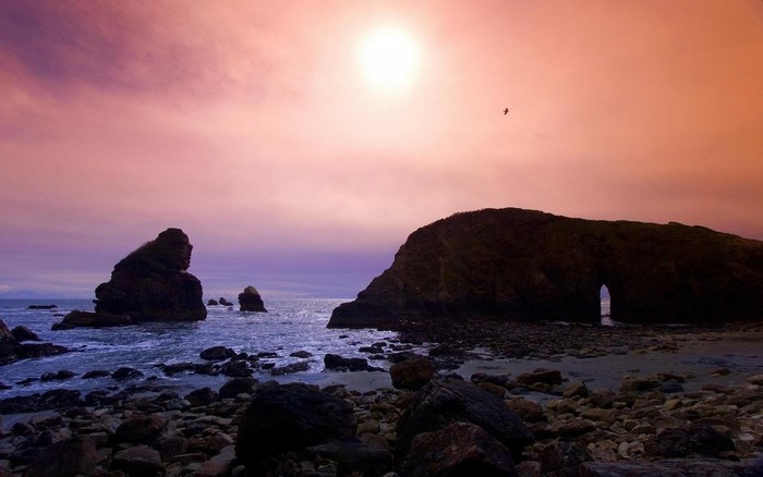 Sunset over rocky coast with sea arch