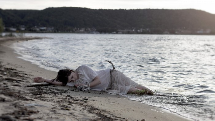 Woman in white dress lying on a sandy beach by the sea
