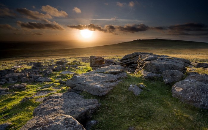 Sunset over rocky moorland with rolling hills