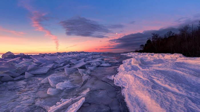 Frozen lake at sunset with pink clouds and moon