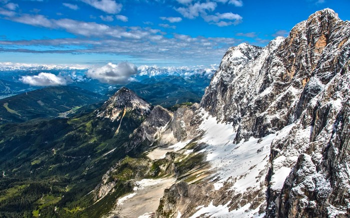 Snow-capped mountains and green valleys under a blue sky