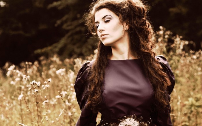 Woman with long brown hair in a purple dress outdoors