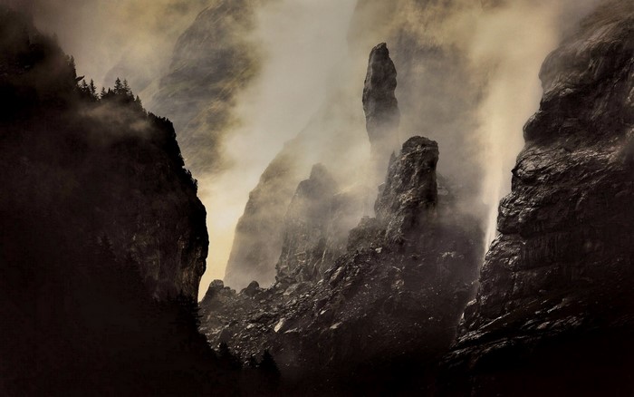 Misty mountain peaks with dark rocks and forest